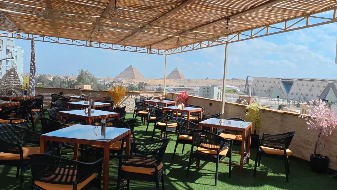 Rooftop terrace at Hostalio Pyramid View at sunset with the Great Pyramids of Giza on the horizon